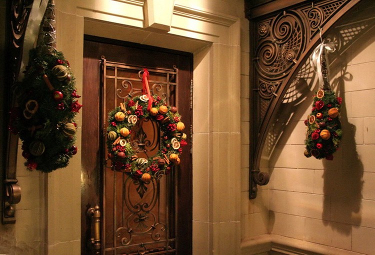 Новогодний венок можно прикрепить к декоративным элементам двери